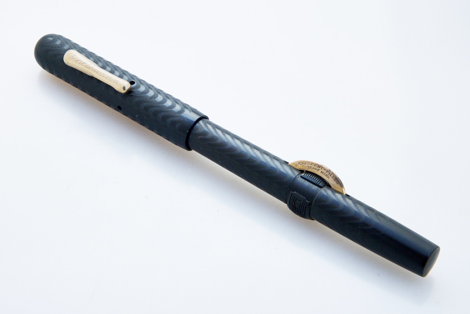 Conklin Crescent-Filler fountain pen in black chased hard rubber, with the gold crescent standing out from the barrel and its locking ring beside it