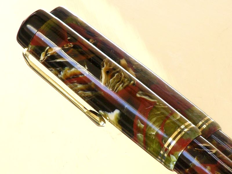 Close-up of a marbled red, green and cream celluloid pen cap with its broken lip rebuilt